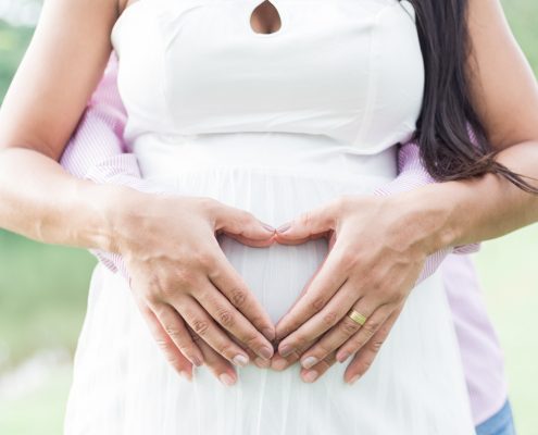 Mãos em formato de coração na barriga