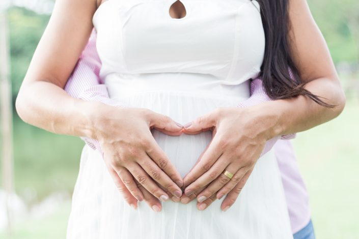 Mãos em formato de coração na barriga