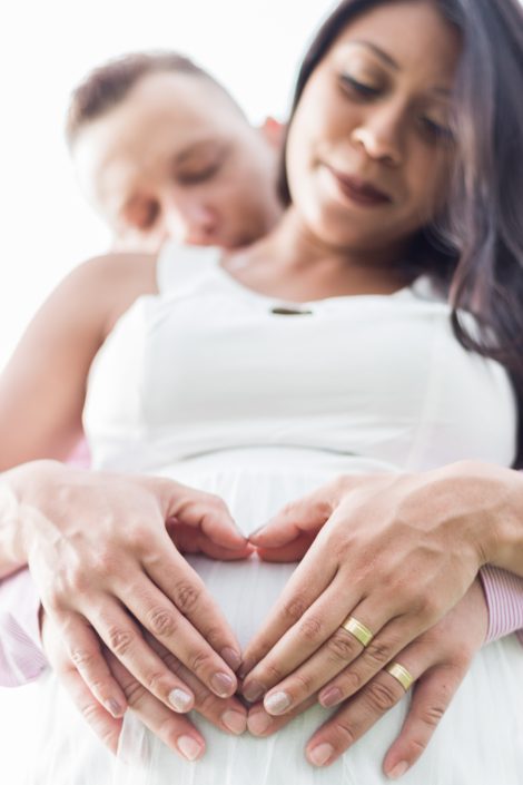 Casal formando coração na barriga com as mãos